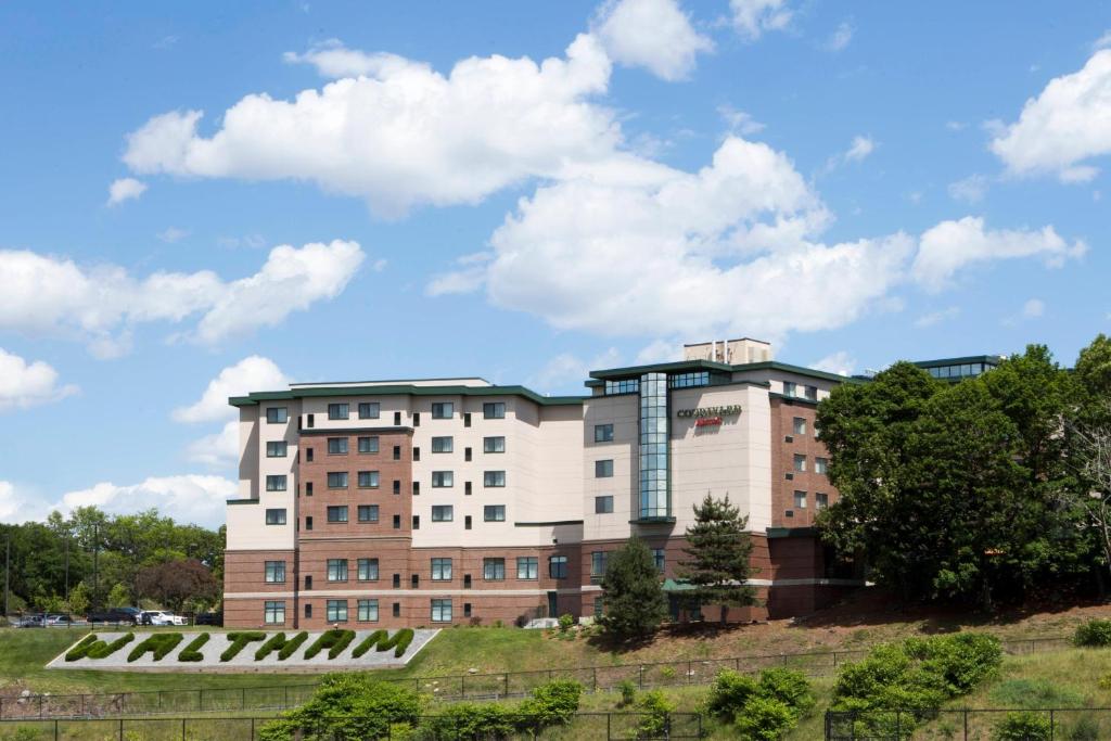 a building on top of a hill with trees at Courtyard by Marriott Boston Waltham in Waltham