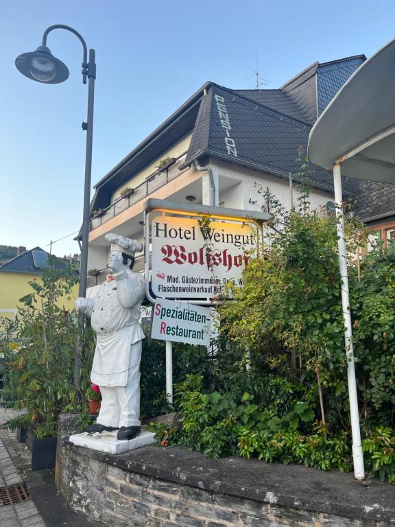 une statue d'un homme debout devant un panneau d'hôtel dans l'établissement Landhotel-Restaurant Wolfshof, à Traben-Trarbach