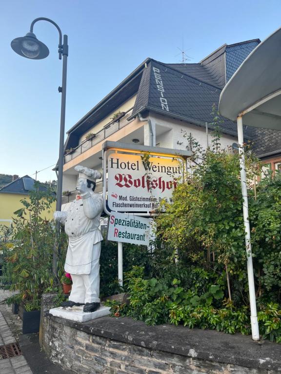 Eine Statue eines Mannes, der vor einem Hotelschild steht. in der Unterkunft Landhotel-Restaurant Wolfshof in Traben-Trarbach