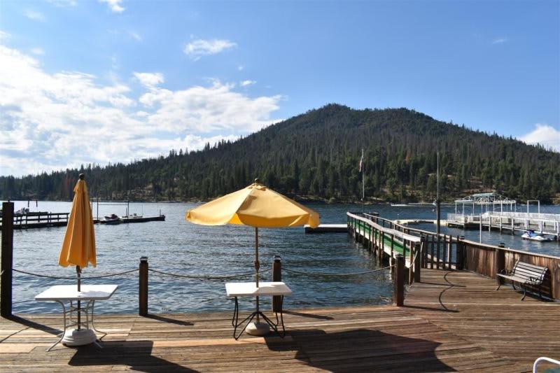 ein Dock mit zwei Stühlen und einem Regenschirm auf dem Wasser in der Unterkunft Charming 1927 Lake Front Home - Hargrave in Bass Lake