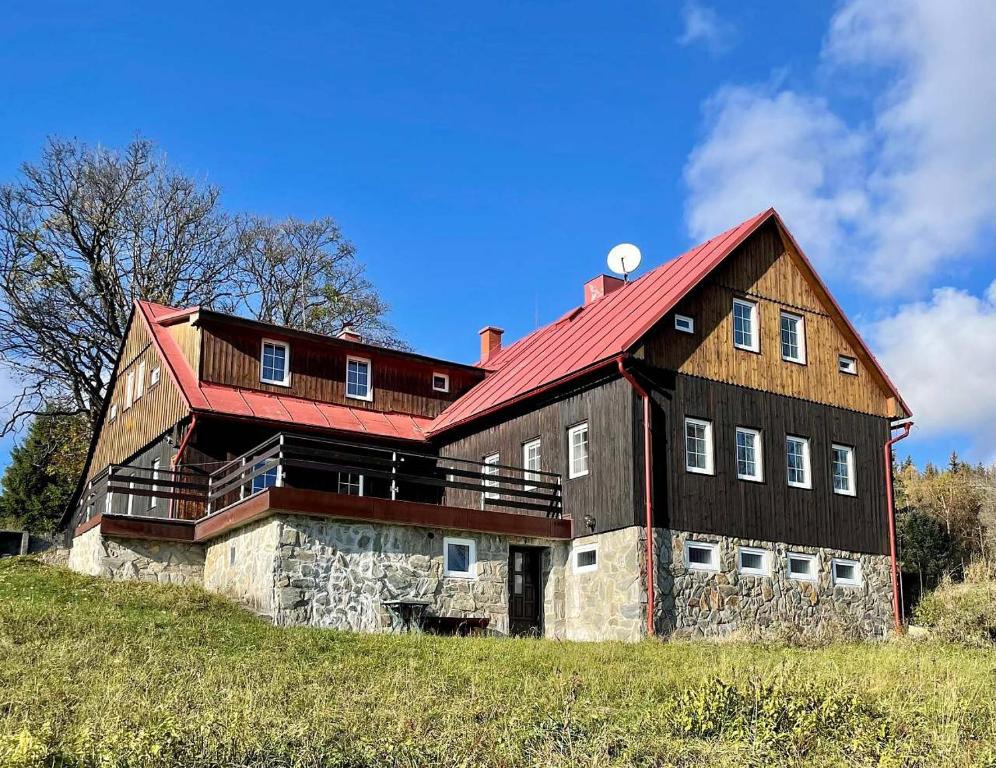 a large barn with a red roof on a hill at Chata VISTA Strážné in Strážné