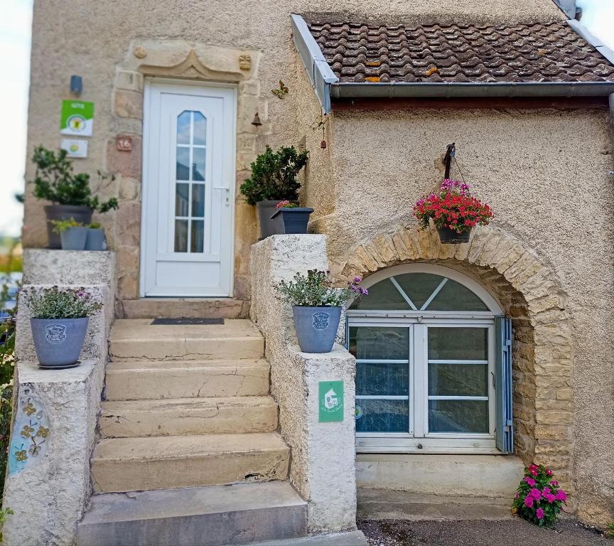 a house with stairs and a door with potted plants at Gîte Le 16, Sous Les Trémières in Fleurey-sur-Ouche