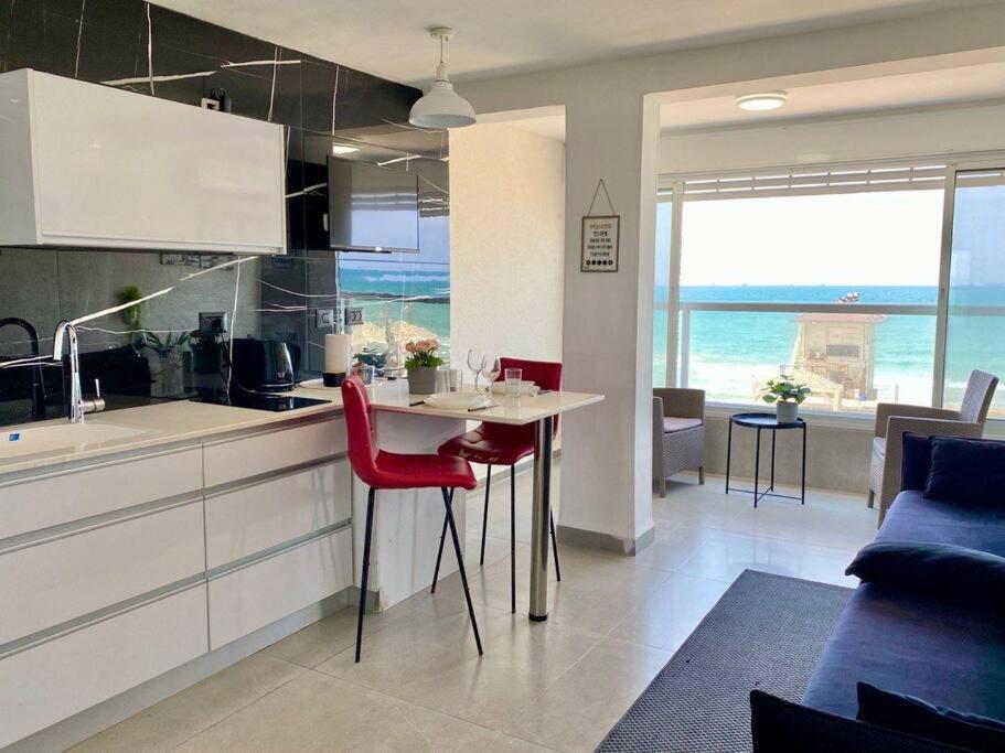 a kitchen with a table and red chairs in a room at Seaside cozy apartment in Haifa