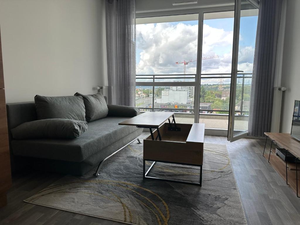 a living room with a couch and a large window at Agréable 2 pièces avec balcon et Parking transports by immo kit bnb in Sarcelles