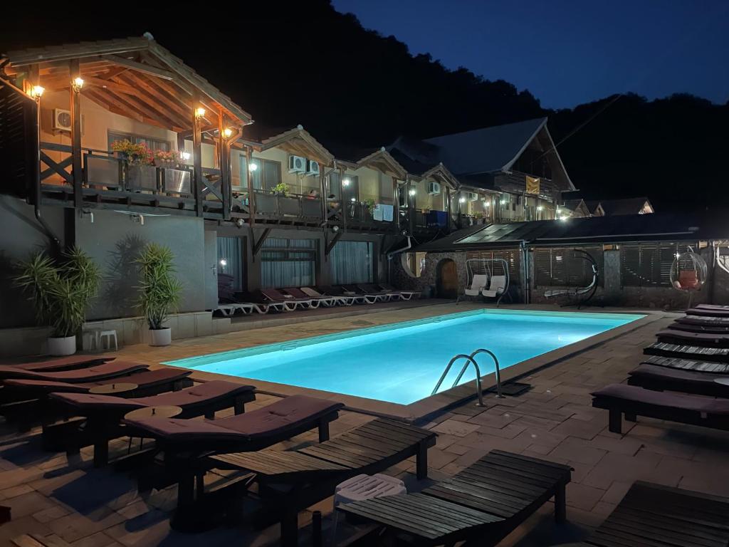 a swimming pool at night with benches around it at Pensiunea Deian-Clisura Dunării in Moldova Nouă