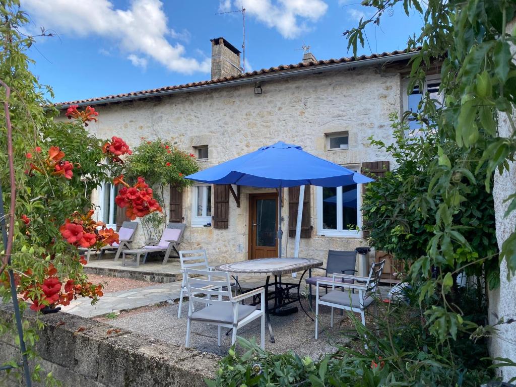 um pátio com uma mesa, cadeiras e um guarda-sol em Pictoresque cottage with pool in Dordogne em Lussas-et-Nontronneau