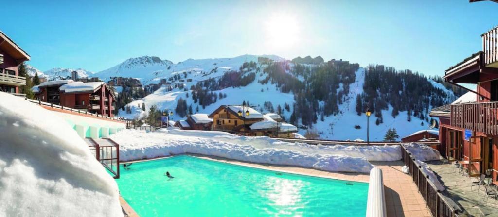 a swimming pool in the snow next to a mountain at Les Silènes & Soldanelle in Plagne 1800