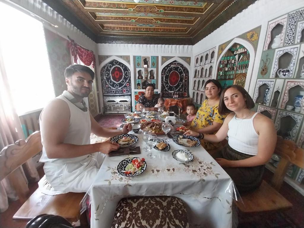 un grupo de personas sentadas alrededor de una mesa con comida en Reyhana Unique House, en Samarkand