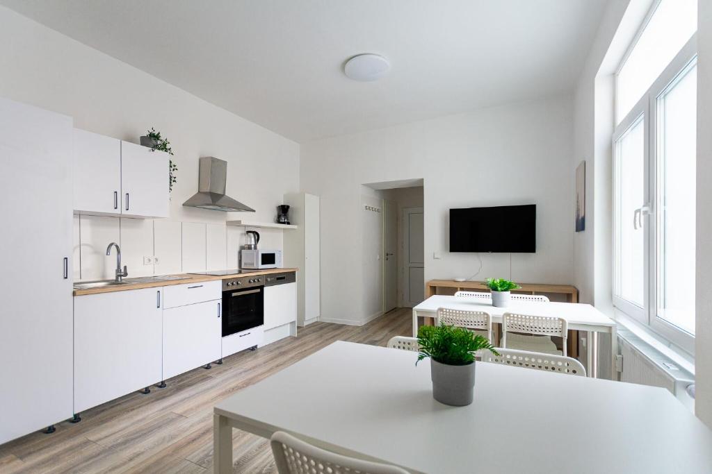 デュースブルクにあるT&K Apartments - 1 to 4 Room Apartments - 20min to TradeFair Messe Airport Düsseldorfの白いキャビネット、テーブルと椅子付きのキッチンが備わります。