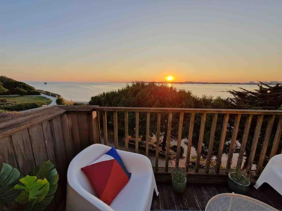 a balcony with a chair and a sunset on the ocean at Appartement aux Minimes Magnifique Vue Mer au pied de la Plage 50m2-2ch. in La Rochelle