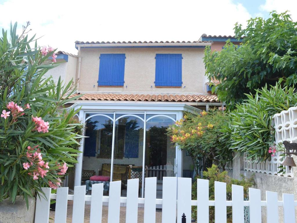une clôture blanche devant une maison avec des volets bleus dans l'établissement Villa 4 pièces avec véranda, proche plage, parking privé et BBQ - Saint Pierre la Mer - FR-1-229D-107, à Fleury