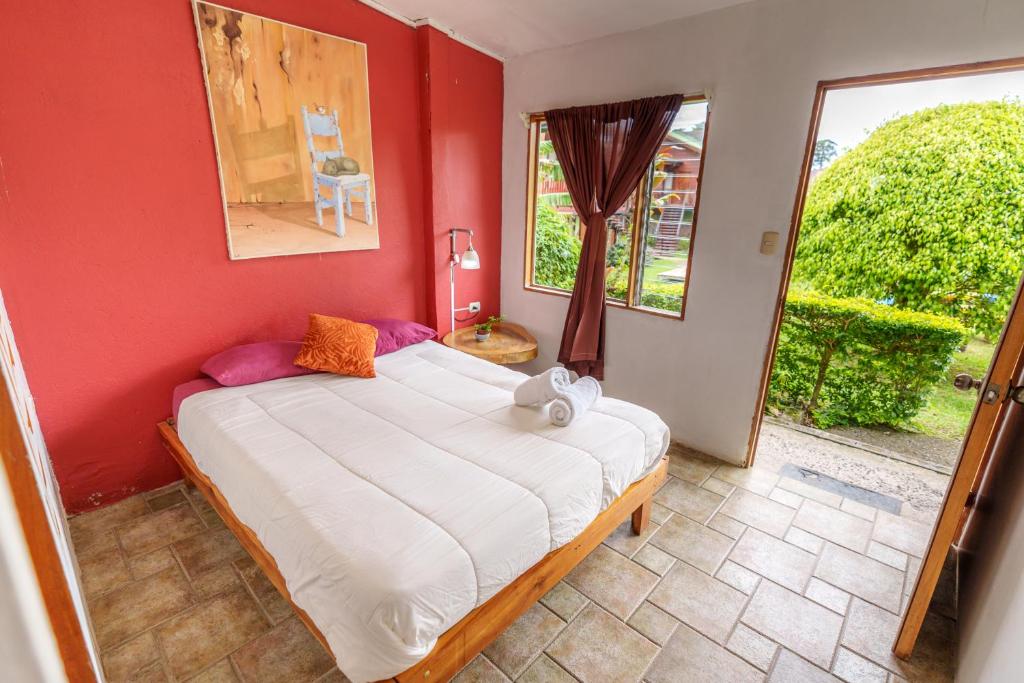 a bedroom with a large bed with a red wall at Pension Santa Elena in Monteverde Costa Rica