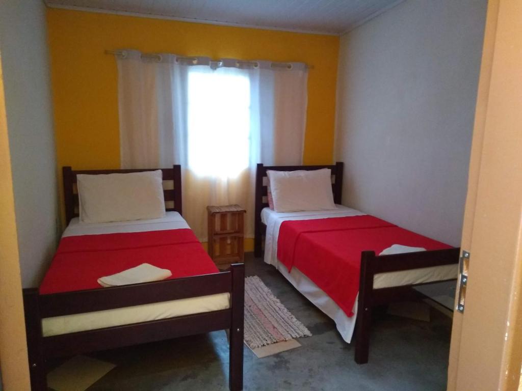 two beds in a small room with a window at Recanto Cheio de Cheiro in Guararema