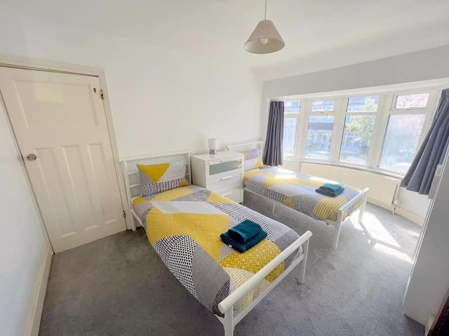 1 dormitorio con 2 camas y 2 ventanas en 4-Bedroom House - South London CR7, en Thornton Heath