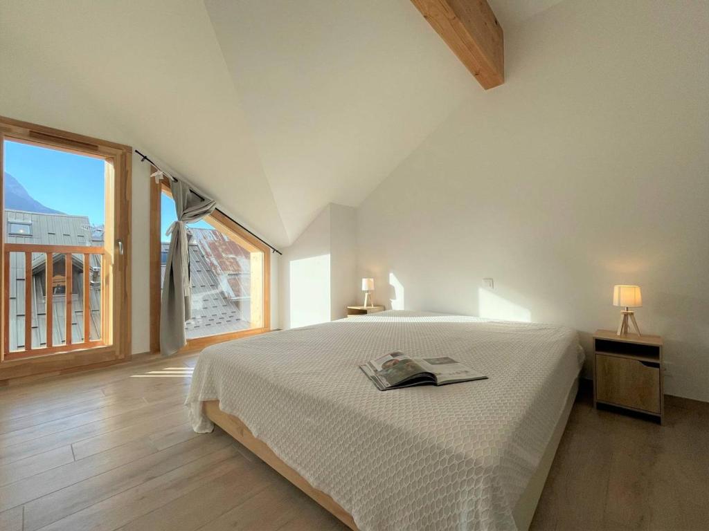 a white bedroom with a bed and a large window at Chalet Puy-Saint-Pierre, 4 pièces, 8 personnes - FR-1-330C-136 in Puy-Saint-Pierre
