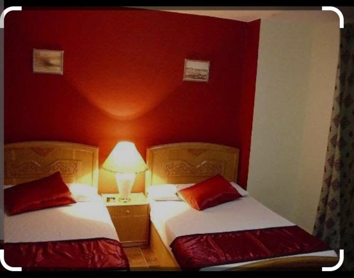 two beds in a room with red walls at Mo Hotel in Cairo