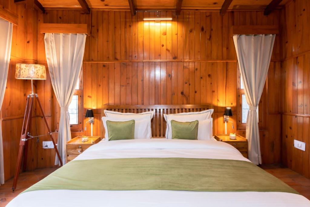 una camera da letto con un grande letto e pareti in legno di The Manora Woods Resort - Private Hill Top, Gethiya, Nainital a Nainital