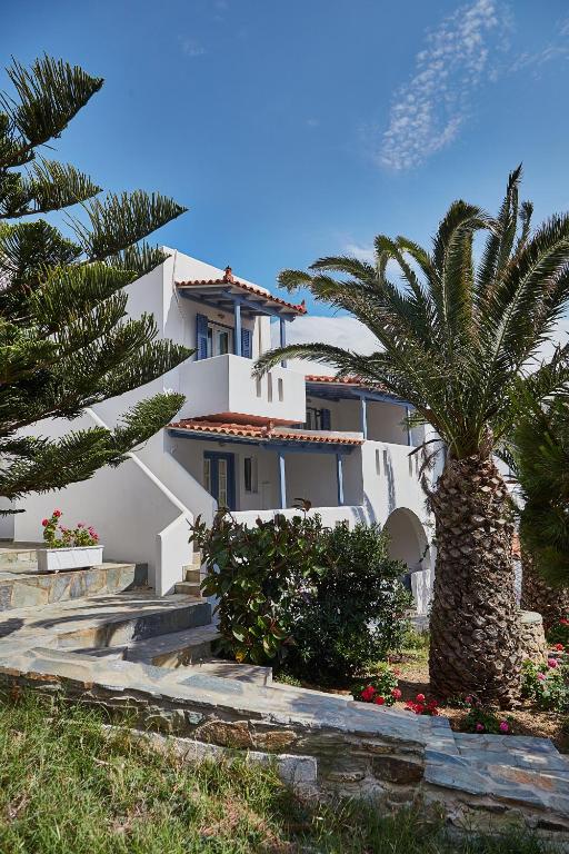 a white house with a palm tree in front of it at Irene Studios in Agios Petros