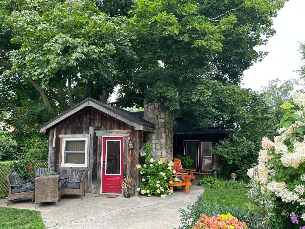 une petite cabine avec une porte rouge dans un jardin dans l'établissement Cozy Guest House close to Wasaga Beach & Blue Mtn, à Nottawa