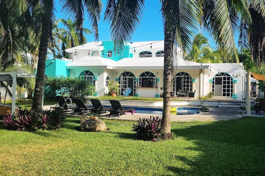 a large white house with palm trees in front of it at Cancun Family ideal Villa, private pool and garden in Cancún
