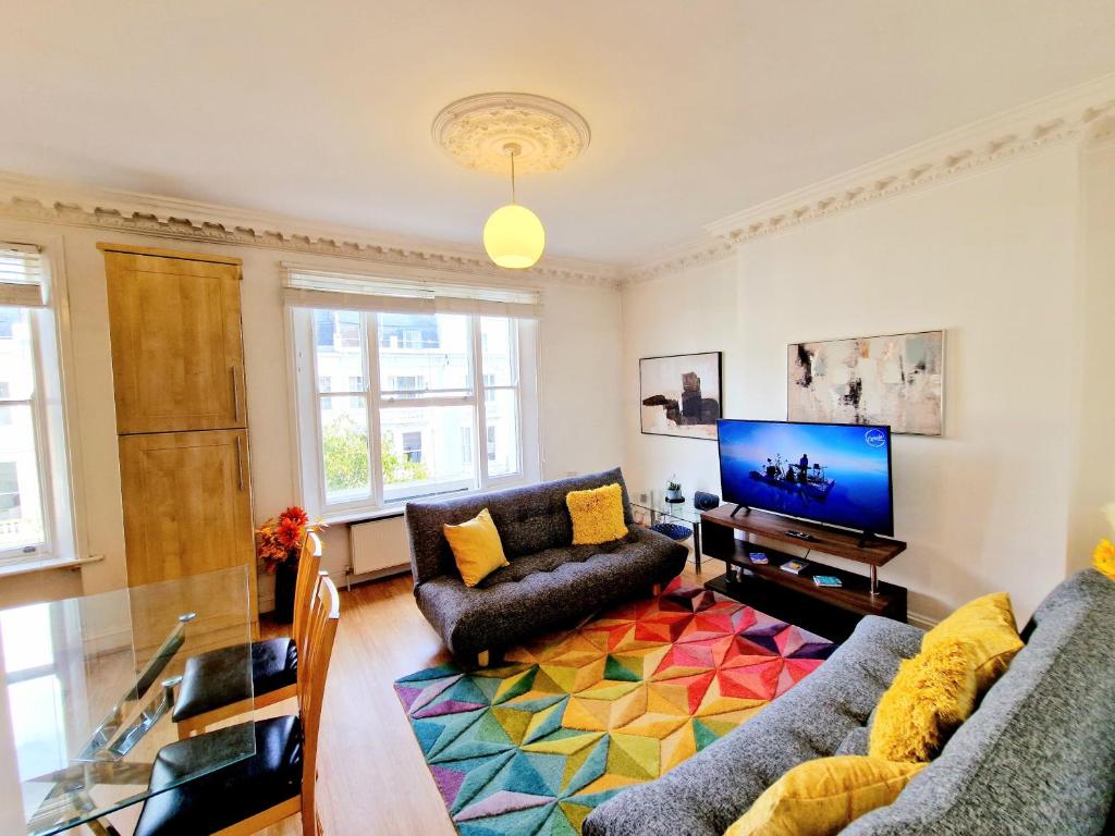 een woonkamer met een bank en een tv bij Beautiful Kensington Home by Earl's Court Station in Londen