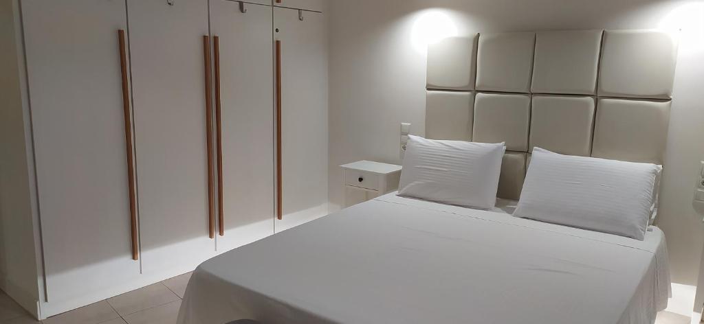 a white bedroom with a large white bed with white pillows at Heraklion City Center Apartment in Heraklio