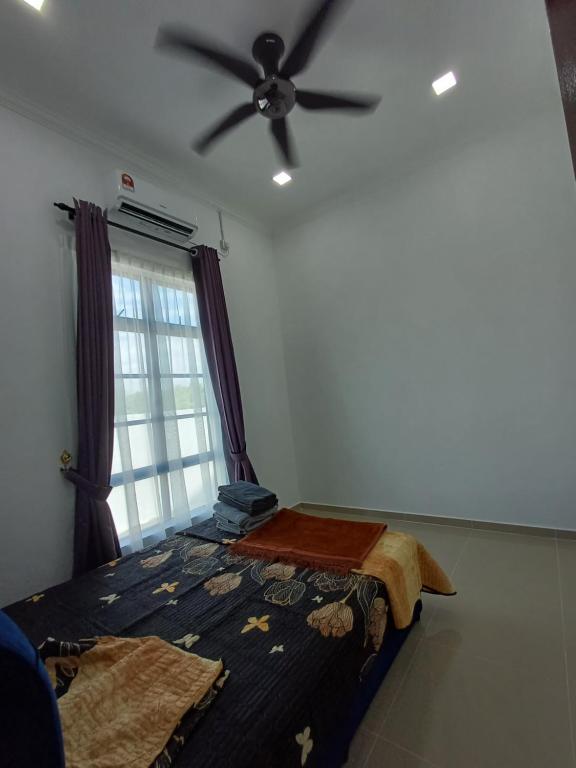 Schlafzimmer mit einem Bett und einem Deckenventilator in der Unterkunft Homestay Besut in Kampung Raja