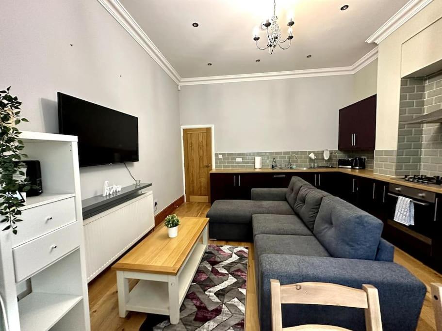 ein Wohnzimmer mit einem grauen Sofa und einer Küche in der Unterkunft 2 Bed Sleeps 6 - Walking distance to Leeds City Centre!! in Leeds