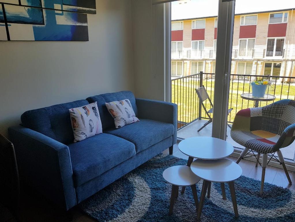 a living room with a blue couch and a table at Depto a orilla del río Calle Calle in Valdivia