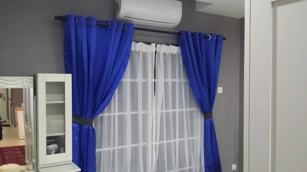 a room with blue and white curtains and a mirror at Champs Elysees in Kampar