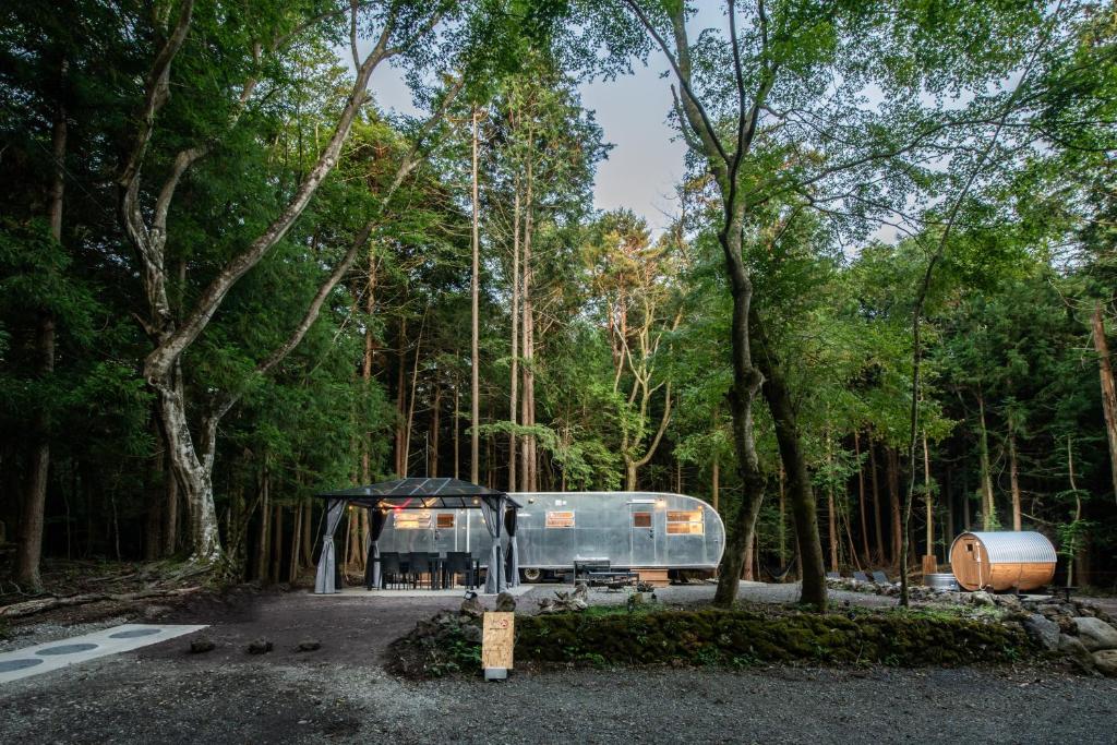 an rv parked in the middle of a forest at 本栖ベース～ヴィンテージトレーラーとバレルサウナ’1日1組限定’の貸切別荘～ in Fujikawaguchiko