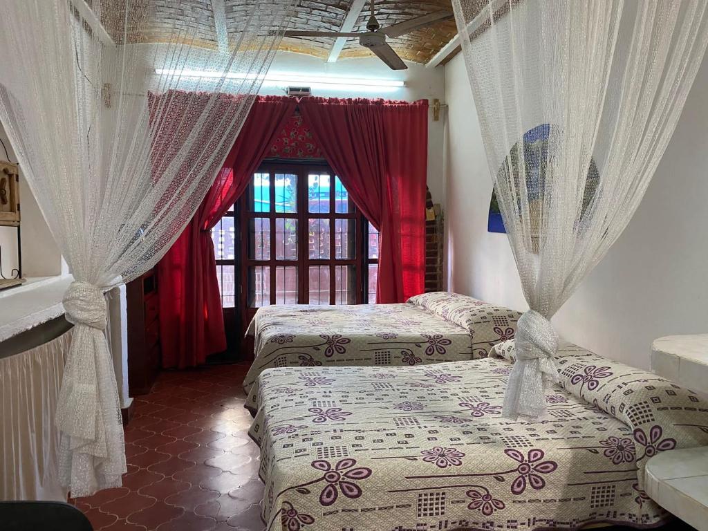 1 dormitorio con 2 camas y una ventana con cortinas en Delias Trailer Park, en Rincón de Guayabitos