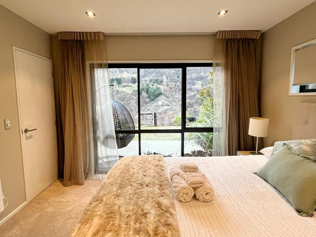 a bedroom with a bed with a large window at Garden Of Eden in Queenstown