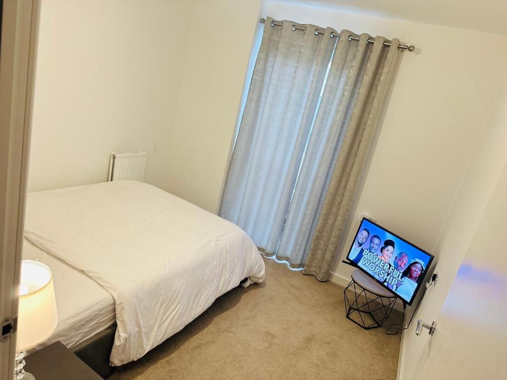 a bedroom with a bed and a flat screen tv at Courtyard tranquil lodge in London