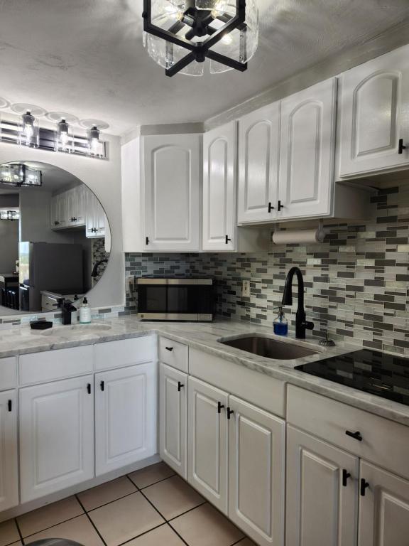 a white kitchen with white cabinets and a sink at Modern Beach Condo-Daytona Beach in Daytona Beach