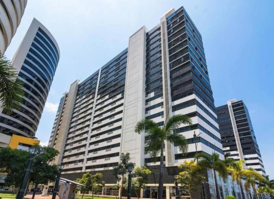 a tall building with palm trees in front of it at Encanto de la Perla del Pacífico in Guayaquil