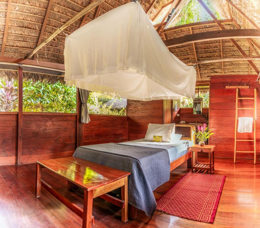 a bedroom with a bed and a large tent at Ecolucerna Lodge Tambopata in Puerto Maldonado