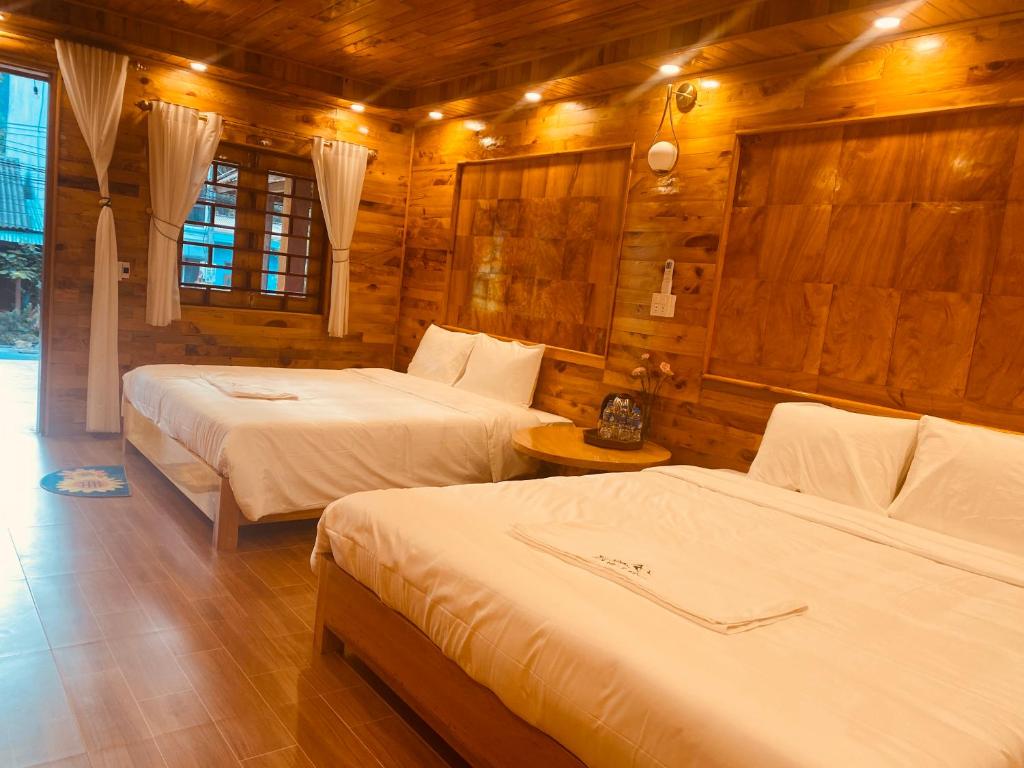 1 dormitorio con 2 camas y pared de madera en Sun Hill's House en Cham Ta Lao