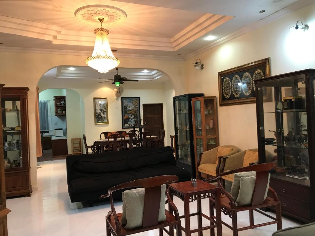 - un salon avec un canapé noir et des chaises dans l'établissement Samba Guest House, Kota Bharu, Kelantan, à Kota Bharu