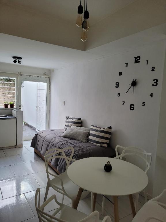a bedroom with a bed and a table and a clock at Departamentos Ines 1 in Junín