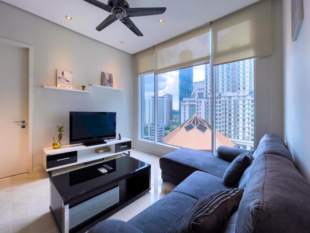 Soho suites klcc by Homestay في كوالالمبور: غرفة معيشة مع أريكة زرقاء وتلفزيون