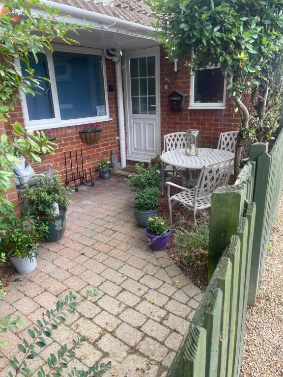 a patio with a table and chairs in front of a house at New Forest View in Beaulieu