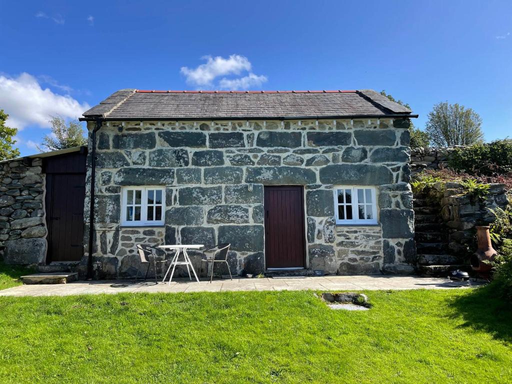 a stone cottage with a table and chairs in front of it at Gelli Bach at Gelli Las in Llanbedr