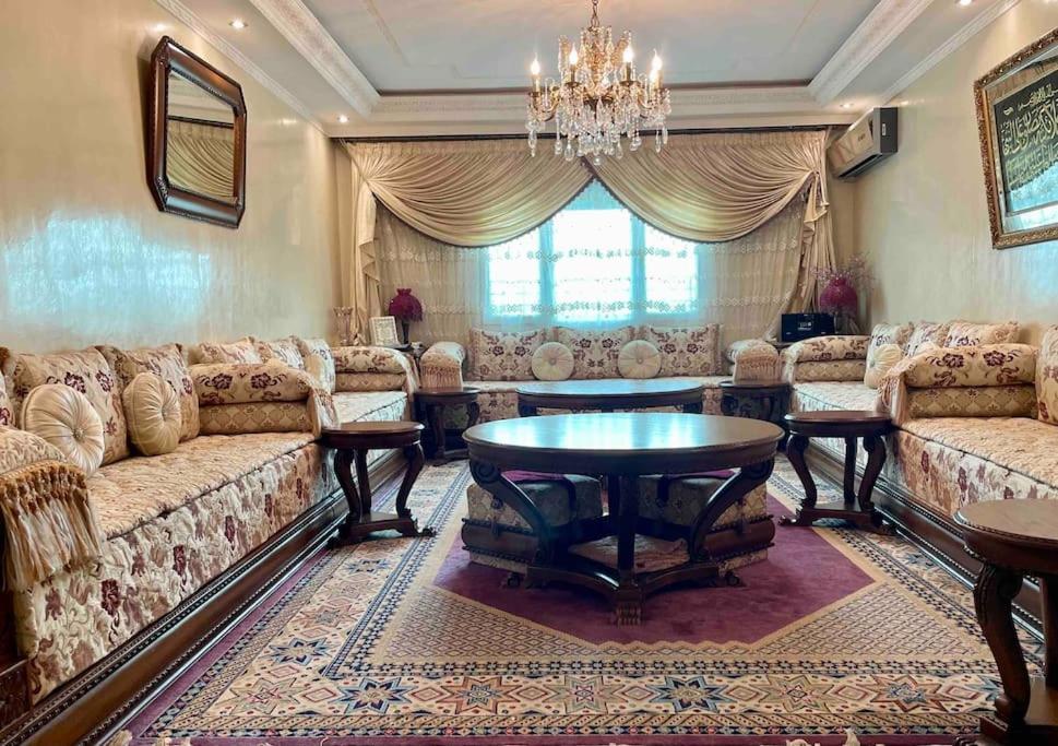 a living room with couches and a table and a chandelier at Appartement de standing calme en centre ville IMAZUR in Tangier