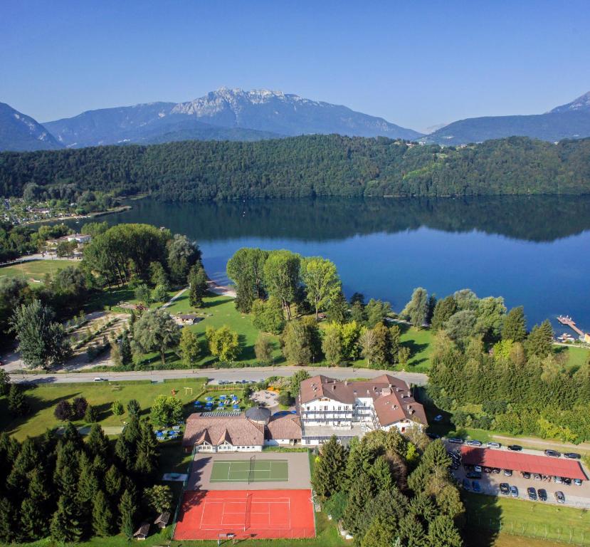 una vista aerea di una casa sulla riva di un lago di Hotel Al Sorriso Greenpark & Wellness a Levico Terme