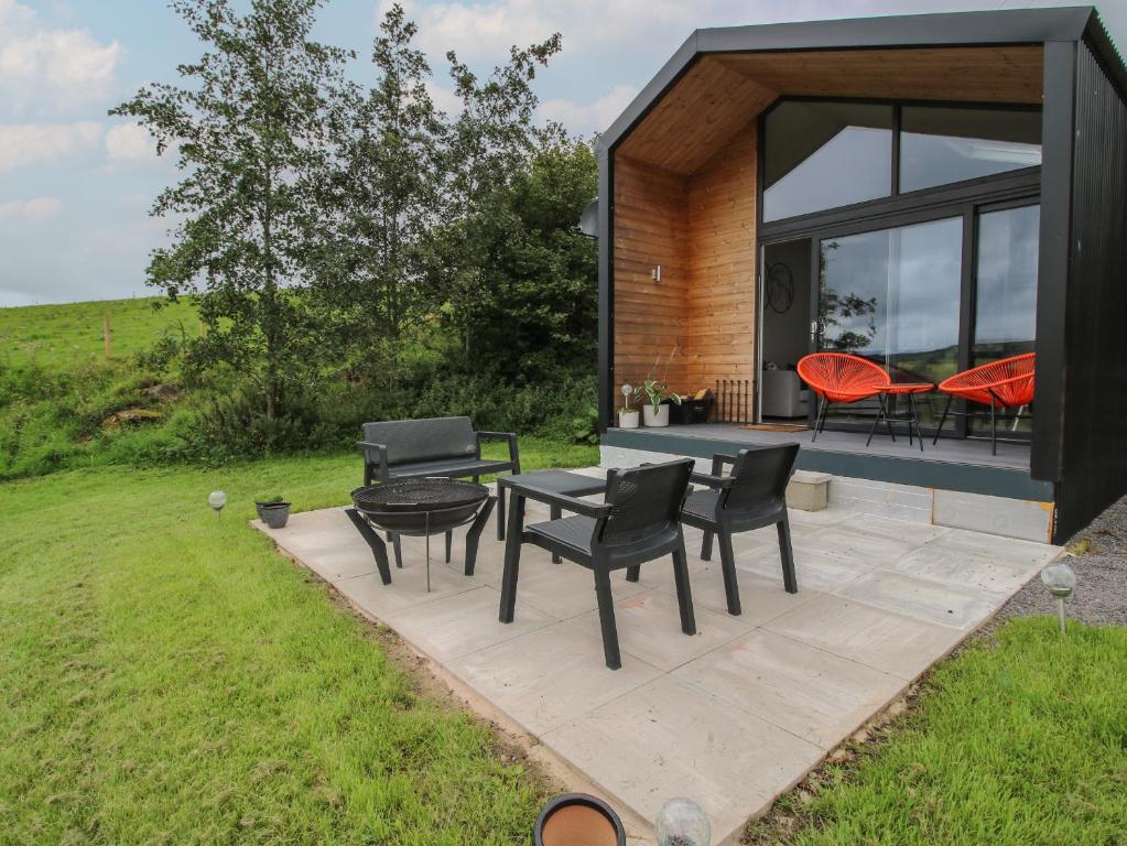 a modern house with black chairs and a table at Little Shelve Barn in Shrewsbury