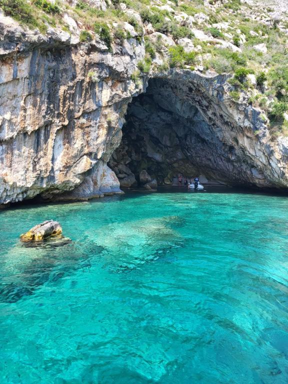 a cave in the water next to a cliff at Augustus Hotel in Dhërmi
