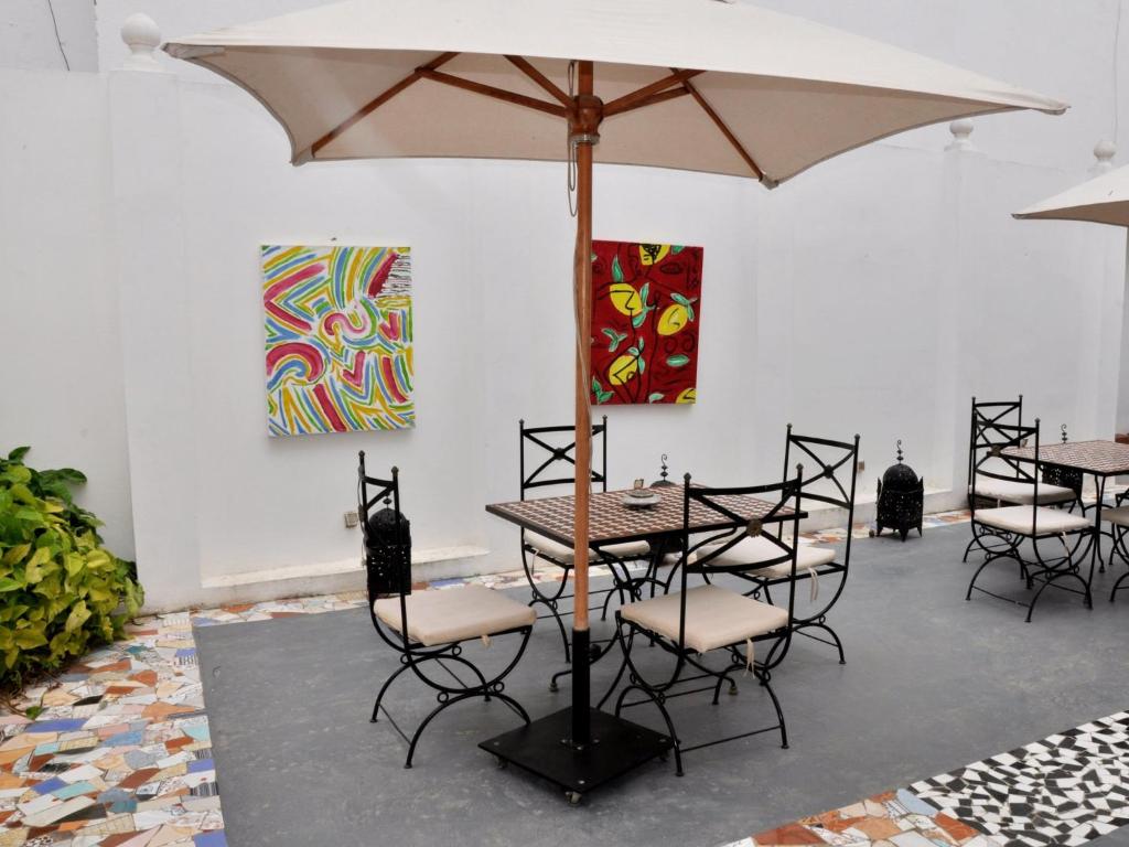 a table and chairs with an umbrella in a room at Hotel Blanco Riad in Tetouan