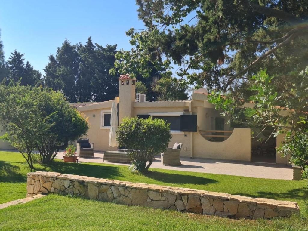 a house with a stone wall in front of a yard at Villa Su Giudeu in Chia