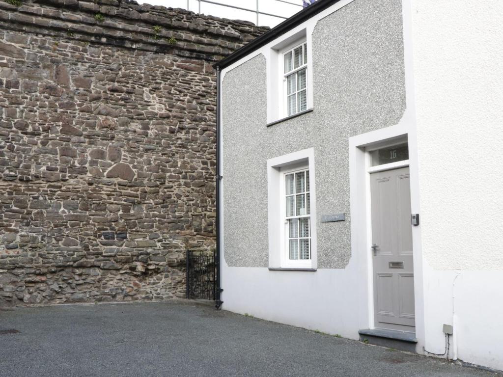 un edificio con una puerta blanca y una pared de ladrillo en Ty Potiwr, en Conwy